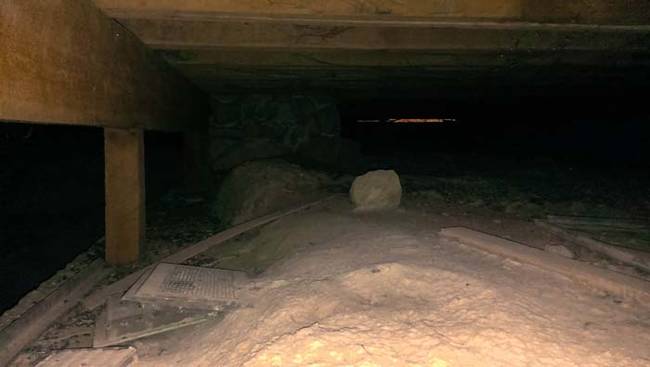 Looking under the floorboards in the basement.