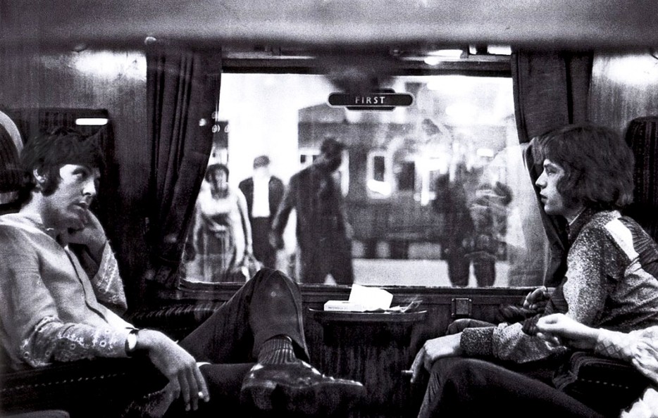 Paul McCartney and Mick Jagger sit opposite each other on a train to Bangor. (1967).