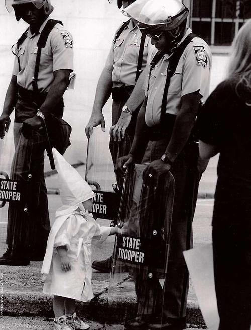 13.) The child KKK member touches his reflection in an African American officer's riot shield during a 1992 demonstration.