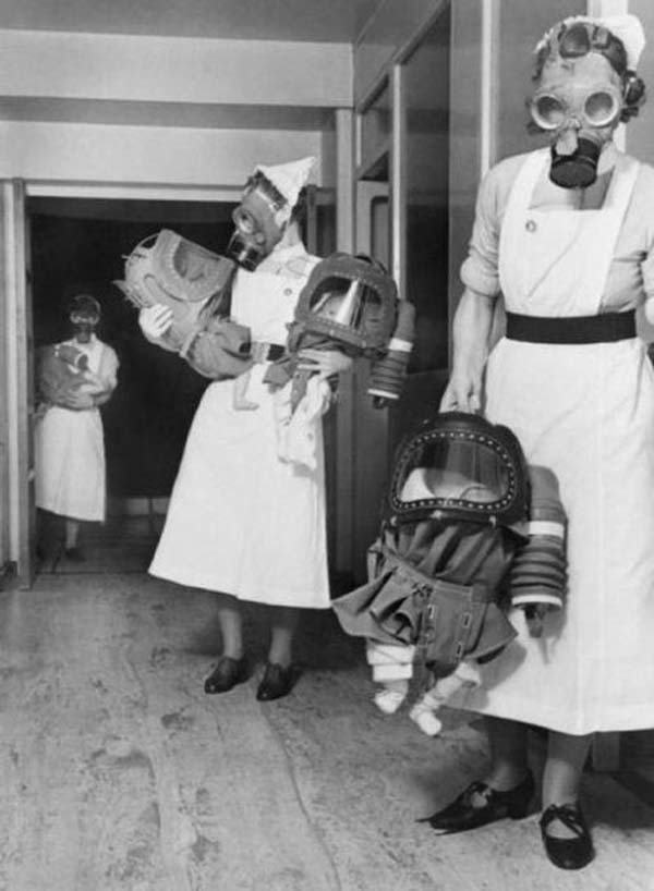 25.) Infants wear gas mask hoods during a London bombing drill (1940).