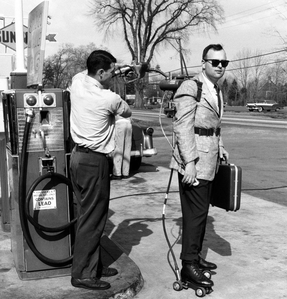 A salesman has his motorized roller skates refueled at a gas station (1961).