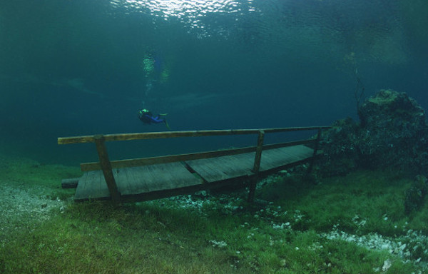 The entire park, benches and all, become submerged under the crystal-clear water from the mountains.