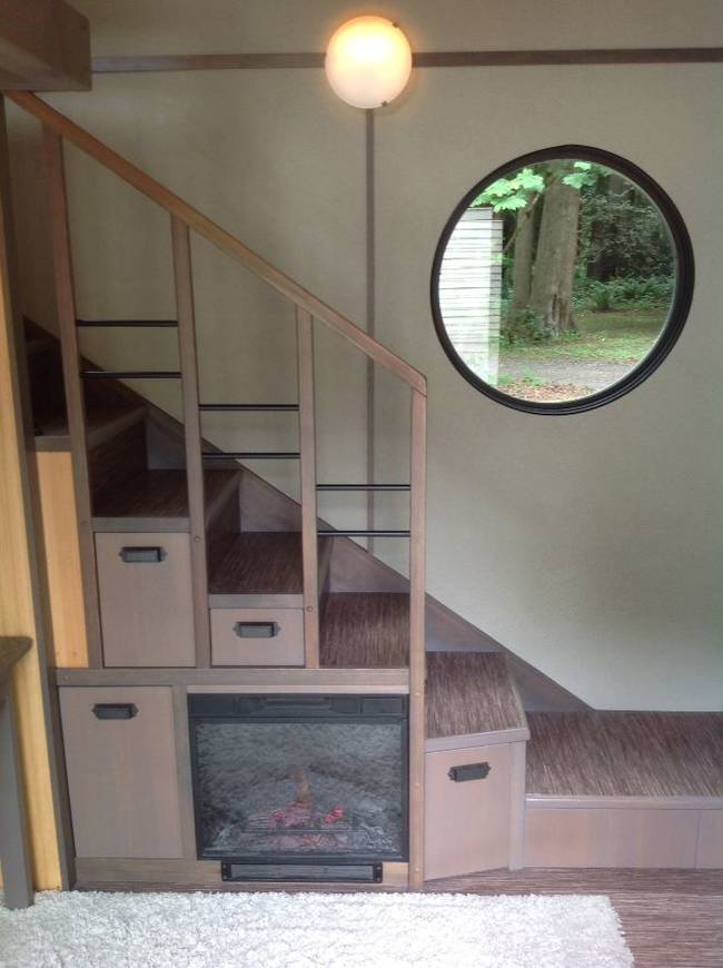 A cozy fireplace sits under the stairs.