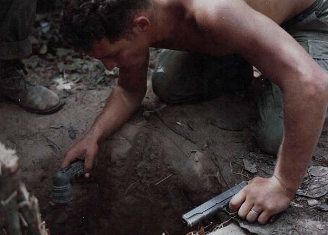 34.) A US Marine prepares to enter a Vietcong tunnel (1969).