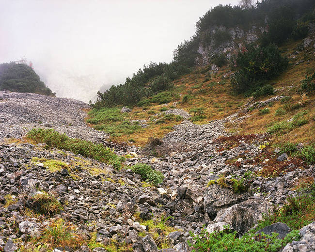 The sniper's muzzle is visible on top of the two big boulders in the lower right corner.