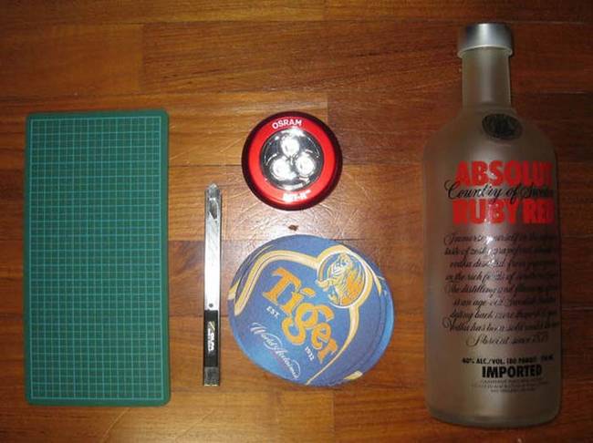 Start out with an empty bottle, cardboard coasters, an LED light and a cutting implement. 