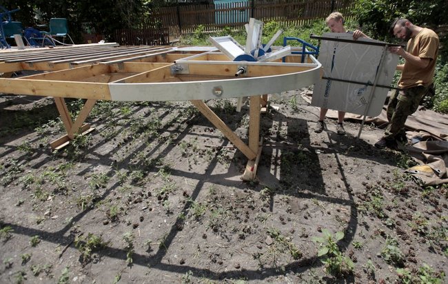 Bures and a friend attaching a rudder to the boat frame.