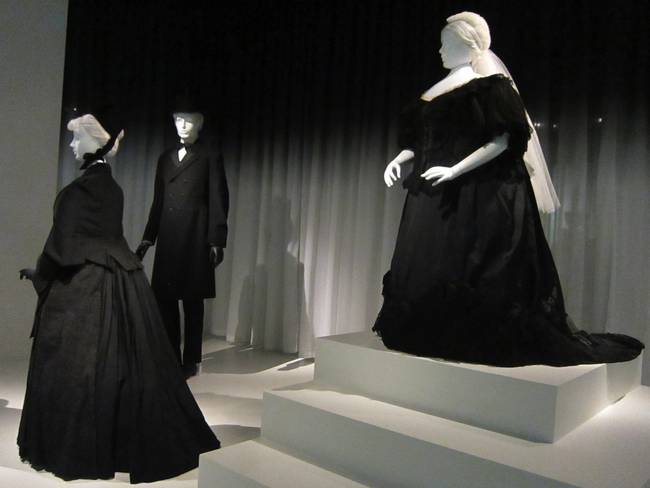 On the left is a woman's and man's mourning attire. On the right is a mourning gown owned by Queen Victoria, who wore mourning garb for the rest of her life after the death of her husband, Prince Albert. Incidentally, Victoria is also responsible for the popularity of the white wedding gown.