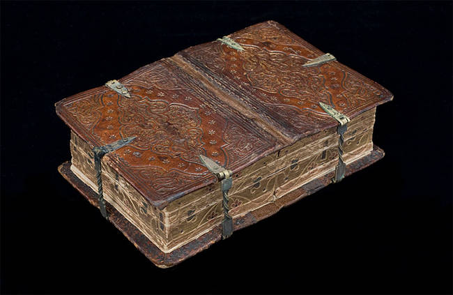 The book when closed, with decorated covers and page edges, as well as metal clasps.