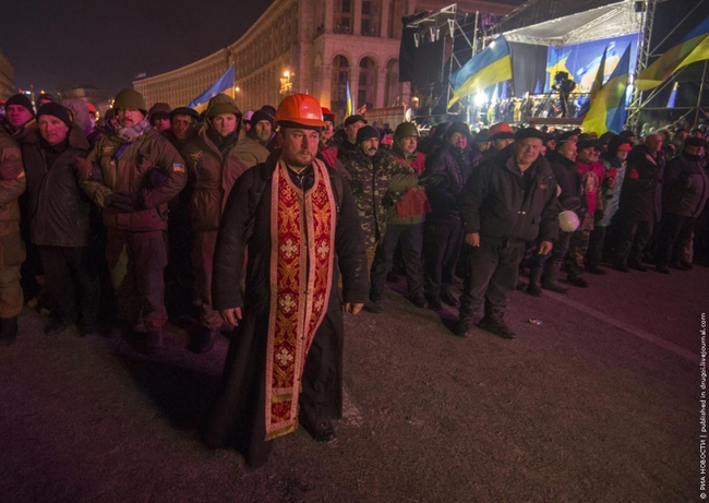 10.) A priest acts as a human shield between protestor and police during protests in Ukraine in 2013.