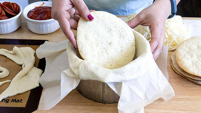 Drape the dough around your pan, letting the sides hang over. Place a cooked and cooled circle of dough at the bottom of the pan.