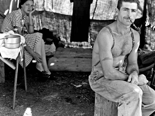 An unemployed lumber worker and his wife following the bean harvest during the Great Depression. His social security number is tattooed on his arm.