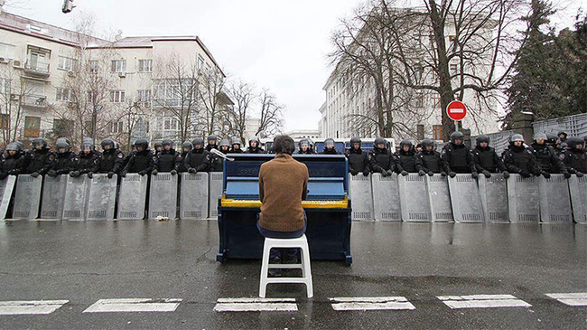 13.) A man plays the piano for riot police in Kiev, Ukraine in 2013.