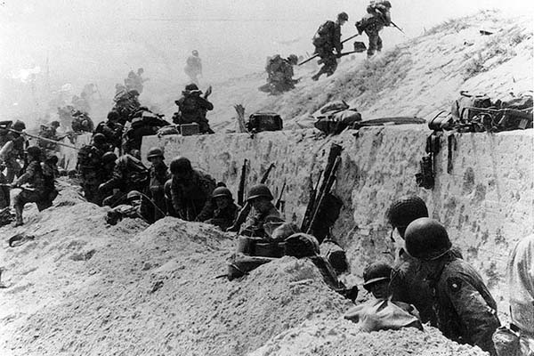 US Army soldiers of the 8th Infantry Regiment, 4th Infantry Division, move out over the seawall on Utah Beach.