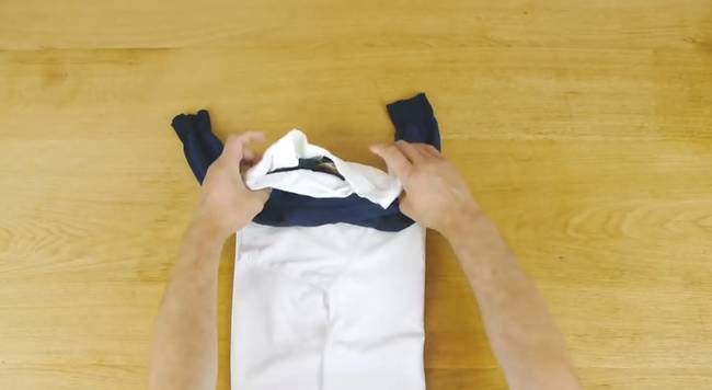 Then place your socks on your shirt, with the open ends of the socks facing out and to the side. From here, begin rolling up your t-shirt.