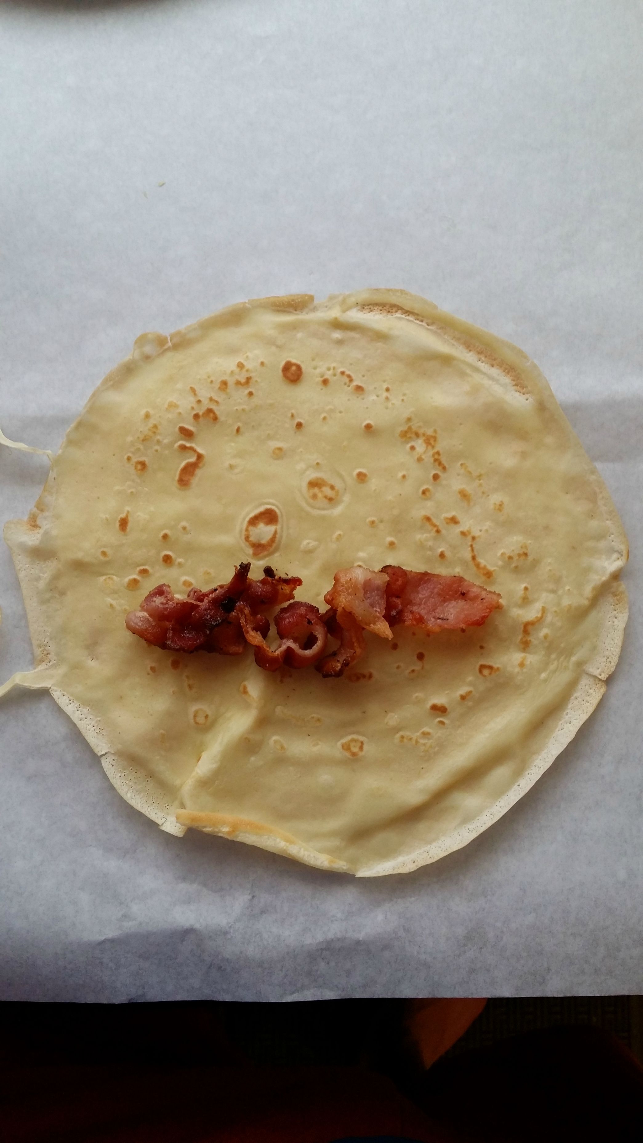 Taking the crepe, he first adds my favorite ingredient... bacon.