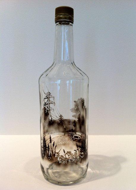 After laying a coat of soot on the lining of the bottles, the artist wipes and etches away with skewers and needles to construct the meticulously defined landscapes.