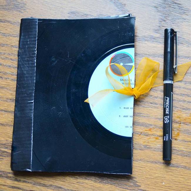 Craft a personalized notebook using an old record and duct tape.