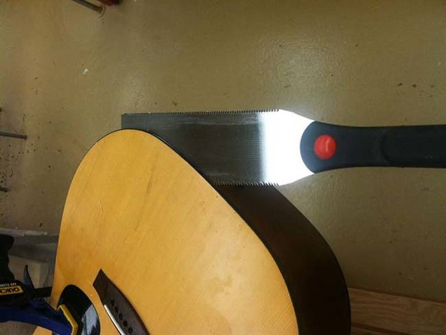 Next, you'll need to remove the face from the guitar. Use a hand saw to cut it off, just make sure to keep the guitar steady with clamps.