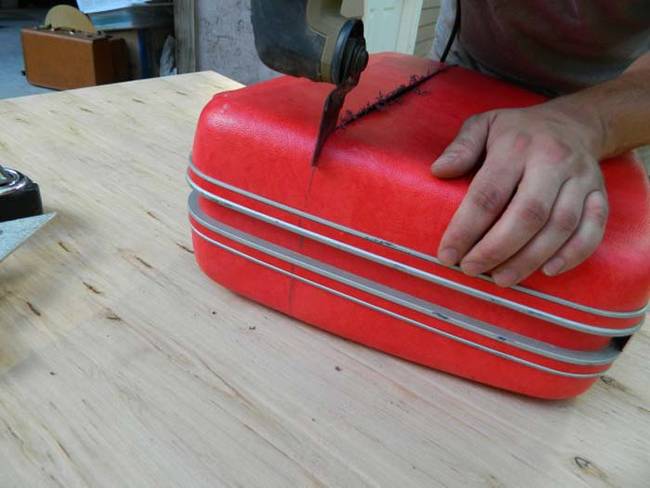 Cut the plastic or hard fabric parts of your suitcase. Once you've reached the metal edge, use a Sawzall to cut through it.