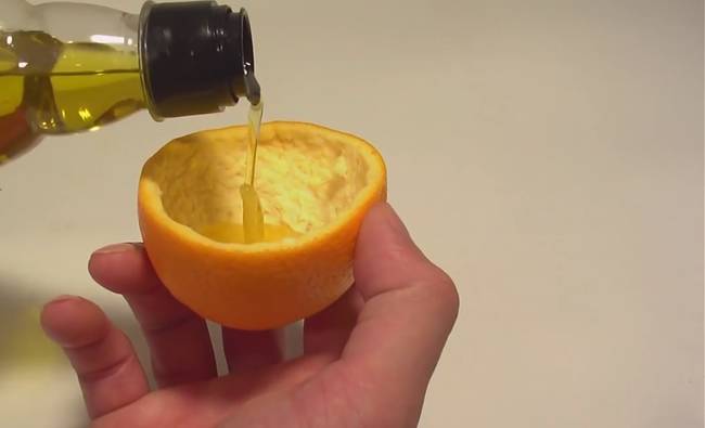 Then pour some olive oil into the orange peel, and be sure to wet the wick as you pour.