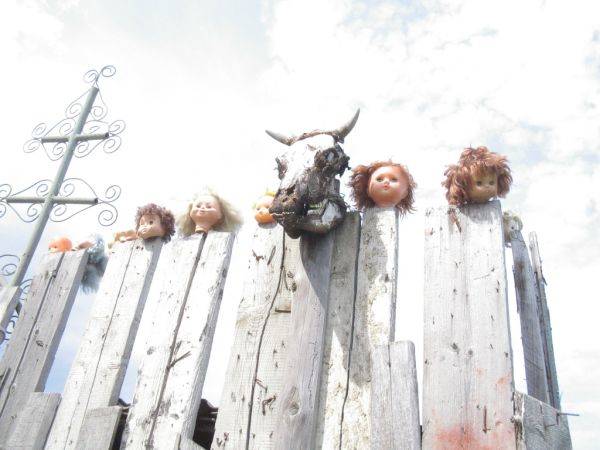 Then you notice something strange on the fence around the property. Something creepy and foreboding. An animal's skull, surrounded by the heads of baby dolls, rests on top of a rotten wooden fence.