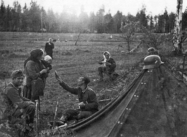 16.) A German soldier share some of his food with a local Russian mother.