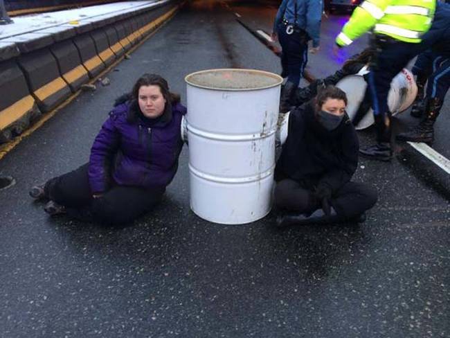 This "protest device," as we'll call it, is a 40 gallon metal drum with a piece of PVC piping going through the middle. The two protesters are handcuffed to each other through the piping. The barrel is then filled with concrete.