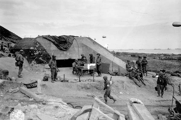 Troops gather near a captured German bunker on D-Day.