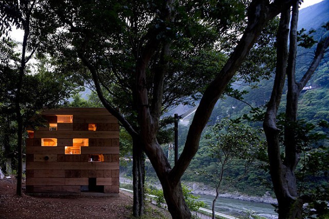 The wooden cube house at dusk. It has lights, too.