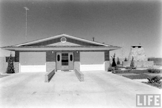 The exterior of the home. From this angle, the house almost looks normal, with two garages and a door, but instead of continuing back, the house continues down. The door also would allow the inhabitants a glimpse of the sun and some fresh air if they weren't feeling too paranoid.