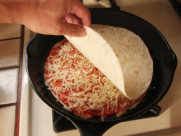 1.) Put a tortilla in a skillet and cover it with pizza sauce and cheese. Put another tortilla on top.